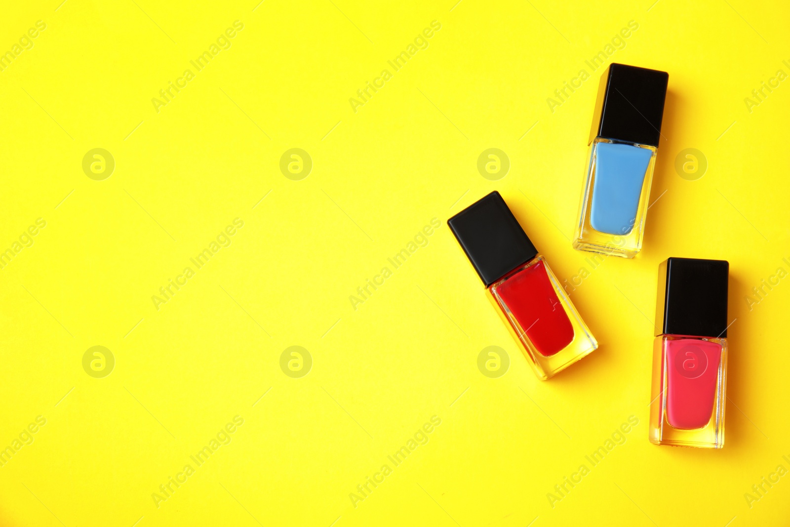 Photo of Bottles of nail polish on color background, top view with space for text