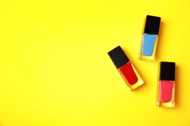 Bottles of nail polish on color background, top view with space for text