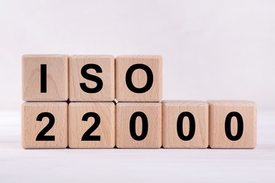 Photo of International Organization for Standardization. Wooden cubes with abbreviation ISO and number 22000 on white table