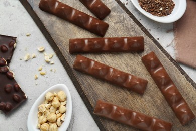 Tasty chocolate bars and nuts on light grey table, flat lay