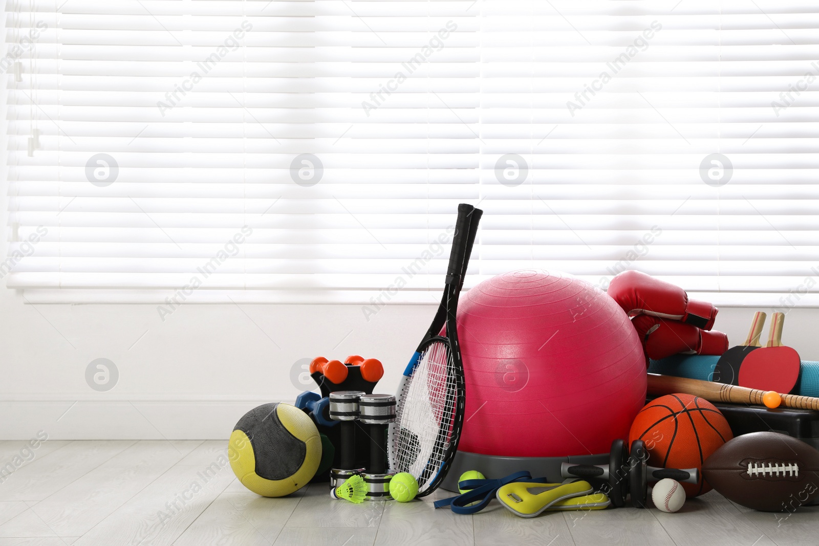 Photo of Set of different sports equipment on white floor indoors, space for text