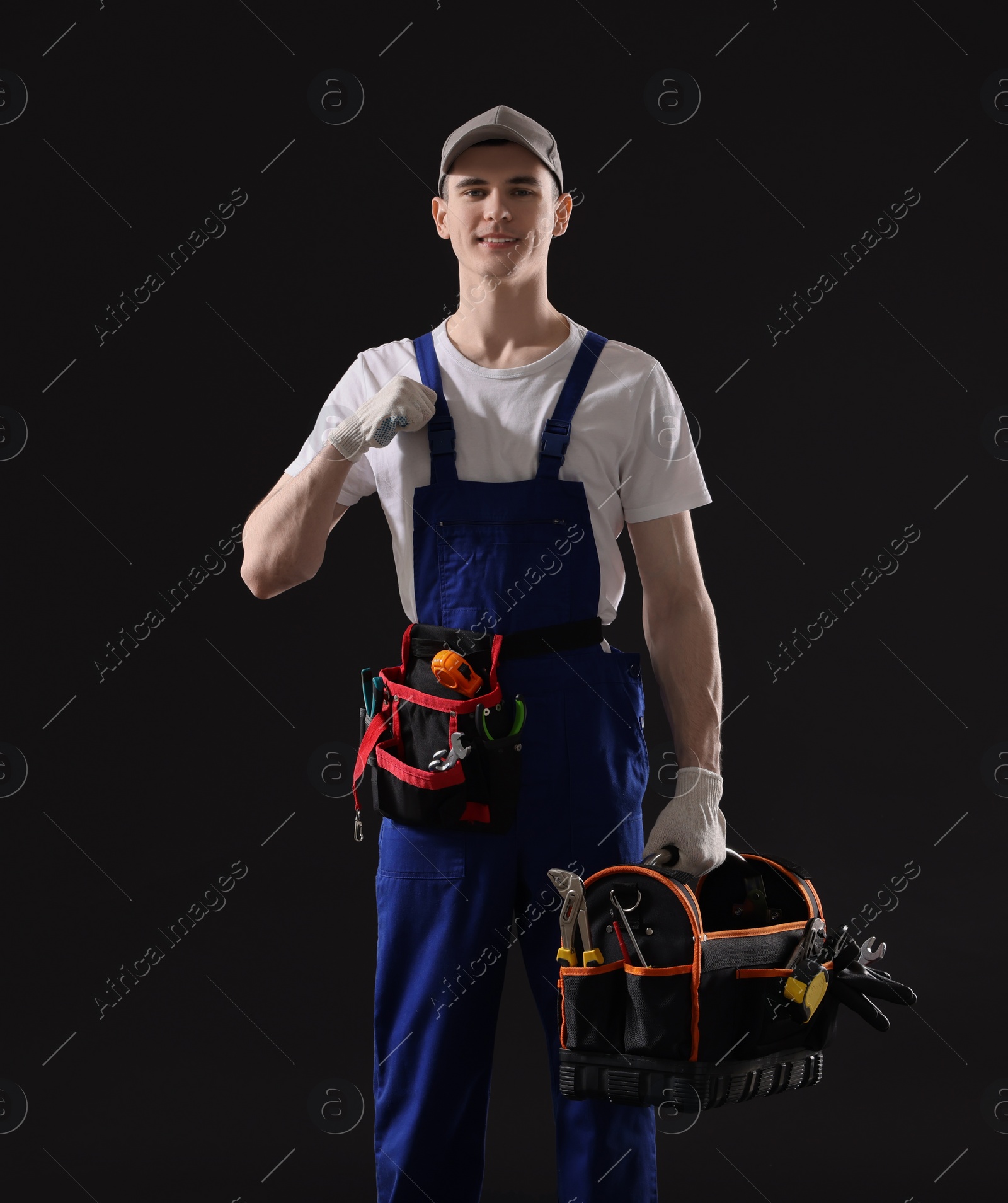 Photo of Professional repairman with tool box on black background