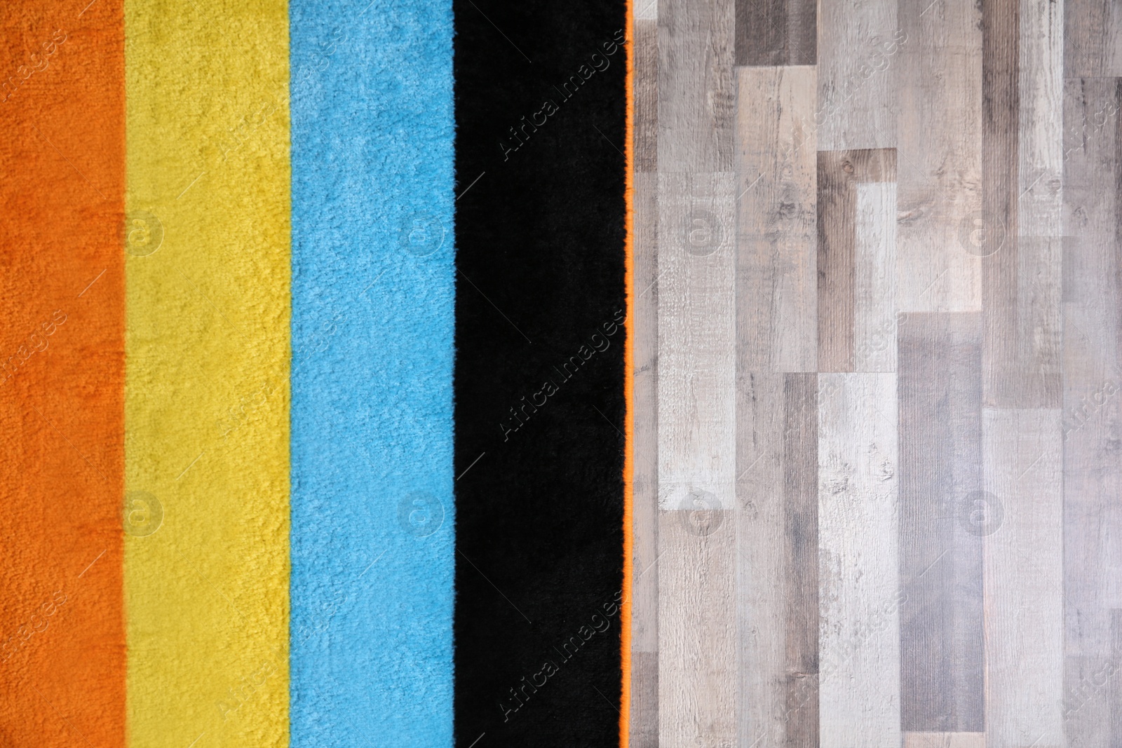 Photo of Colorful striped carpet on wooden floor