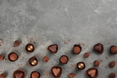 Different delicious chocolate candies on grey table, flat lay. Space for text