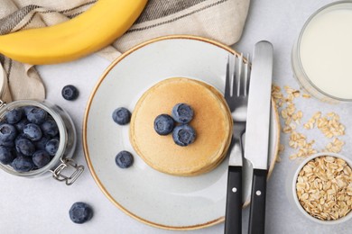 Photo of Tasty oatmeal pancakes and ingredients on grey table, flat lay