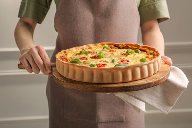 Photo of Woman with delicious homemade cheese quiche indoors, closeup