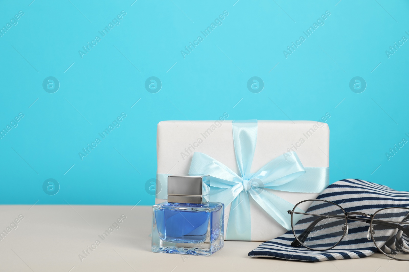 Photo of Happy Father's Day. Tie, glasses, perfume and gift box on beige table, closeup. Space for text