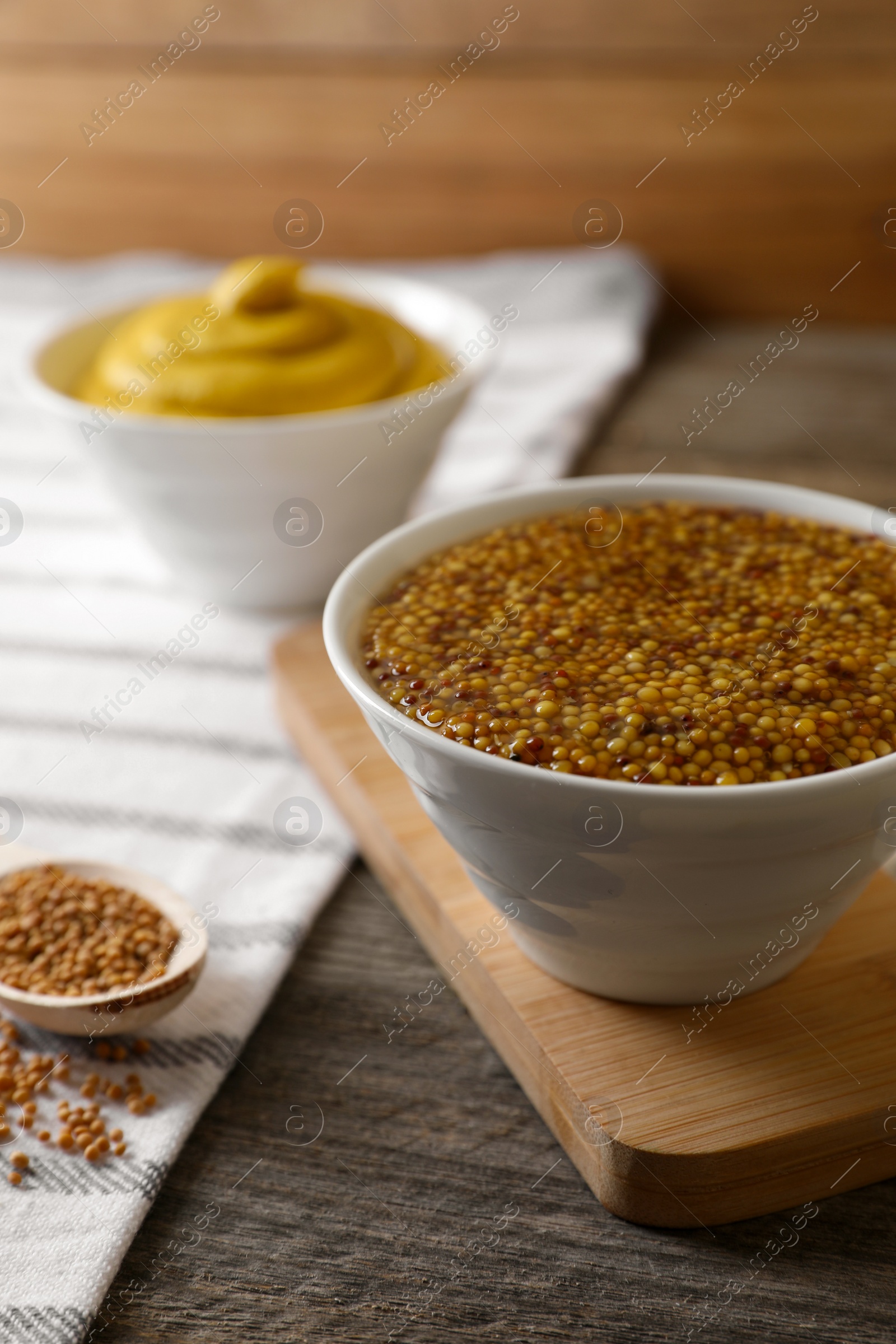 Photo of Bowl of whole grain mustard on wooden table, closeup. Space for text