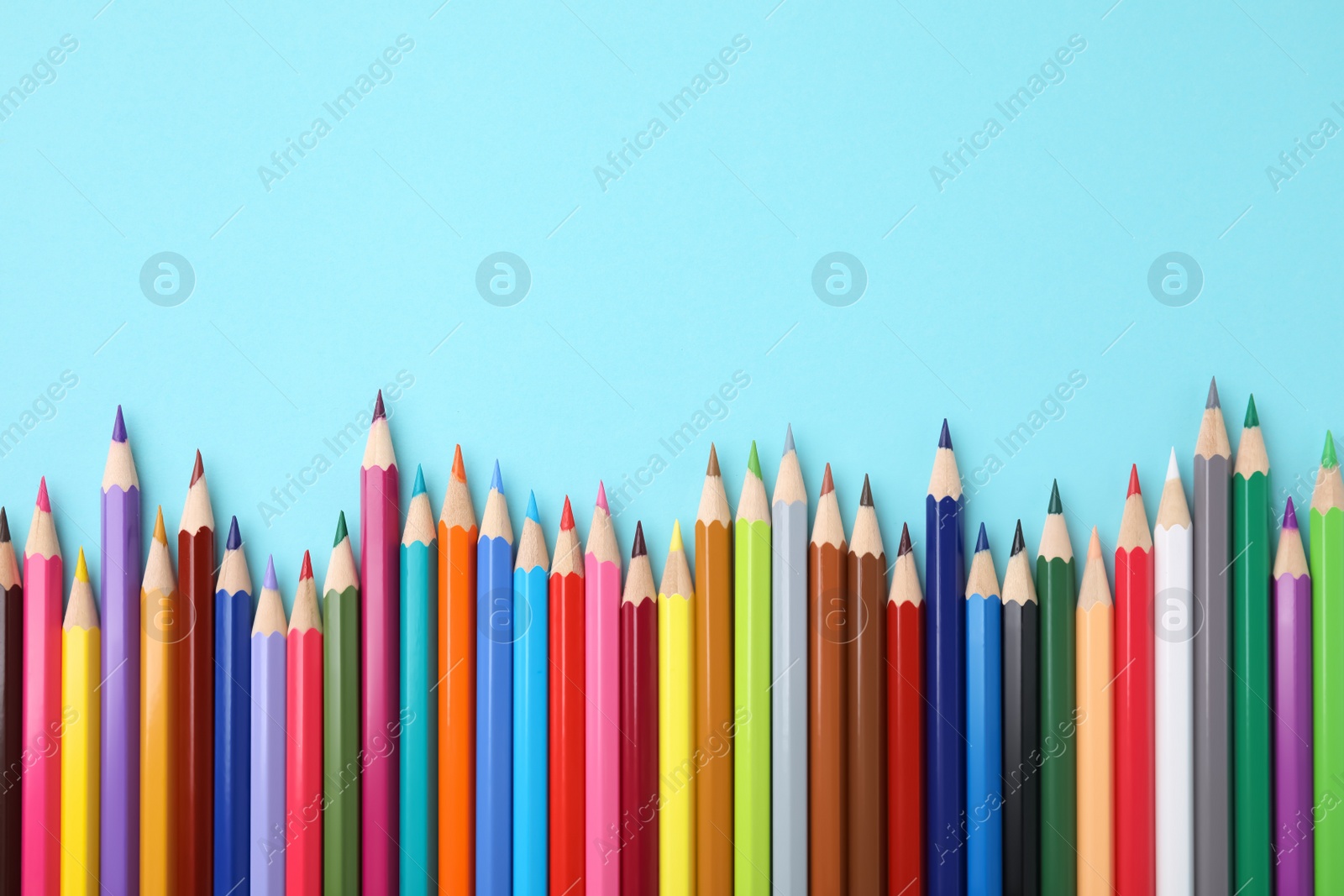 Photo of Colorful wooden pencils on light blue background, flat lay. Space for text