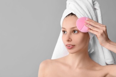 Photo of Washing face. Young woman with cleansing brush on grey background, space for text