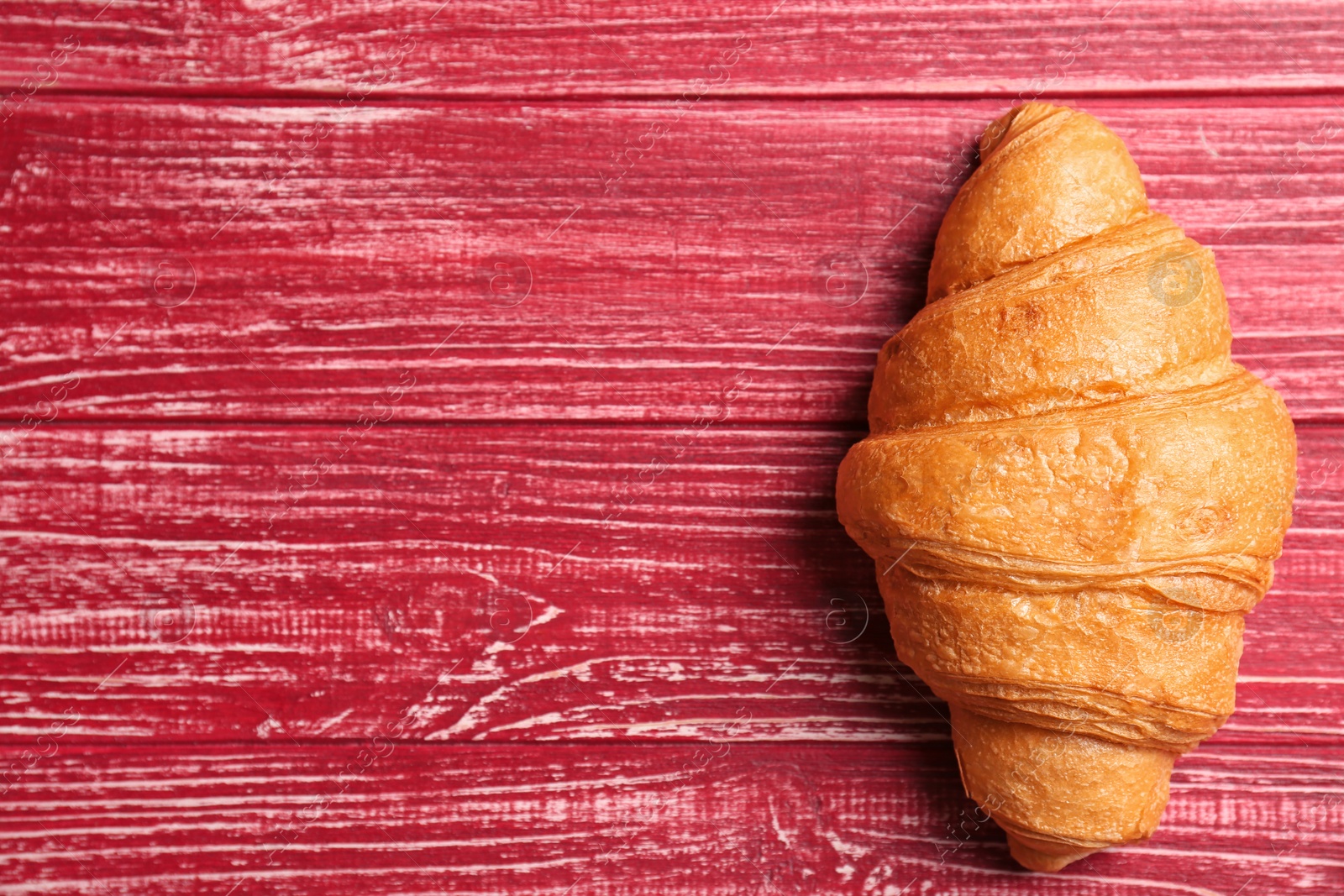 Photo of Tasty croissant on wooden background, top view