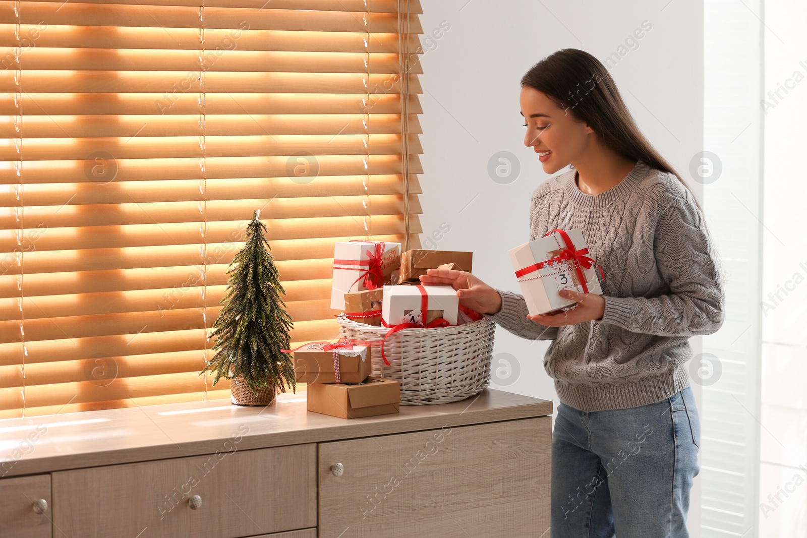 Photo of Woman with Christmas gifts at home. Advent calendar in basket