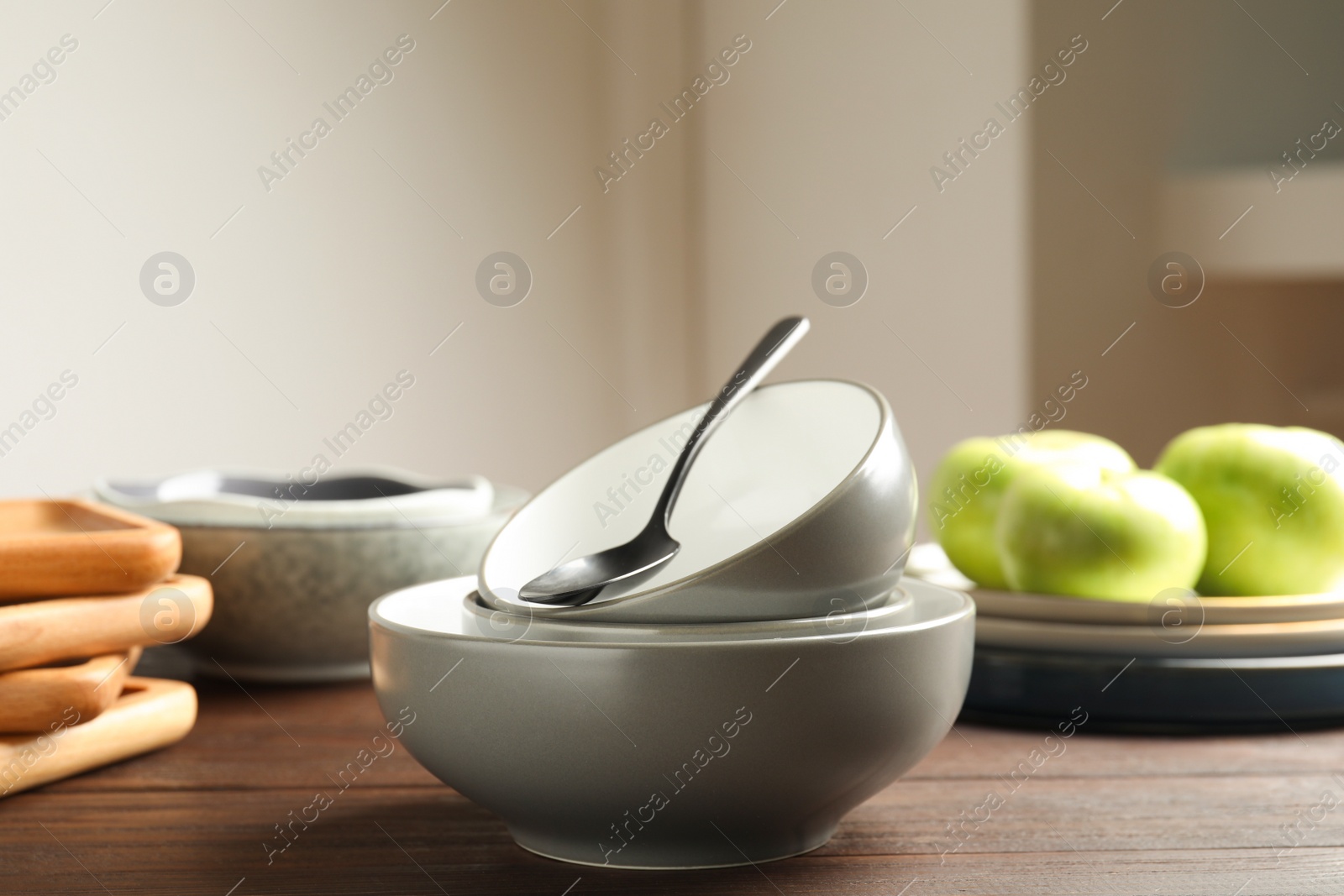 Photo of Grey ceramic bowls and spoon on wooden table indoors