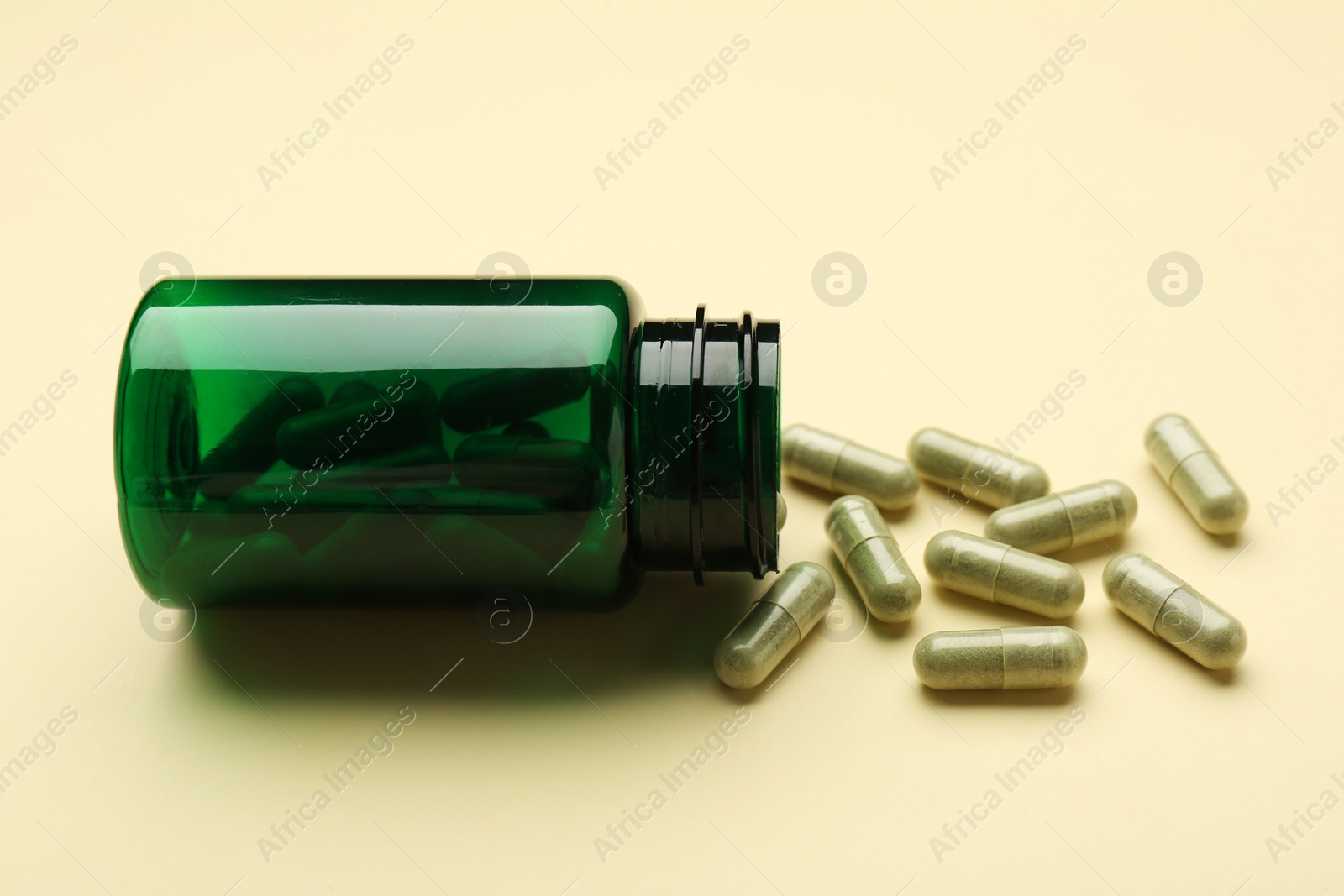 Photo of Vitamin pills and bottle on beige background, closeup