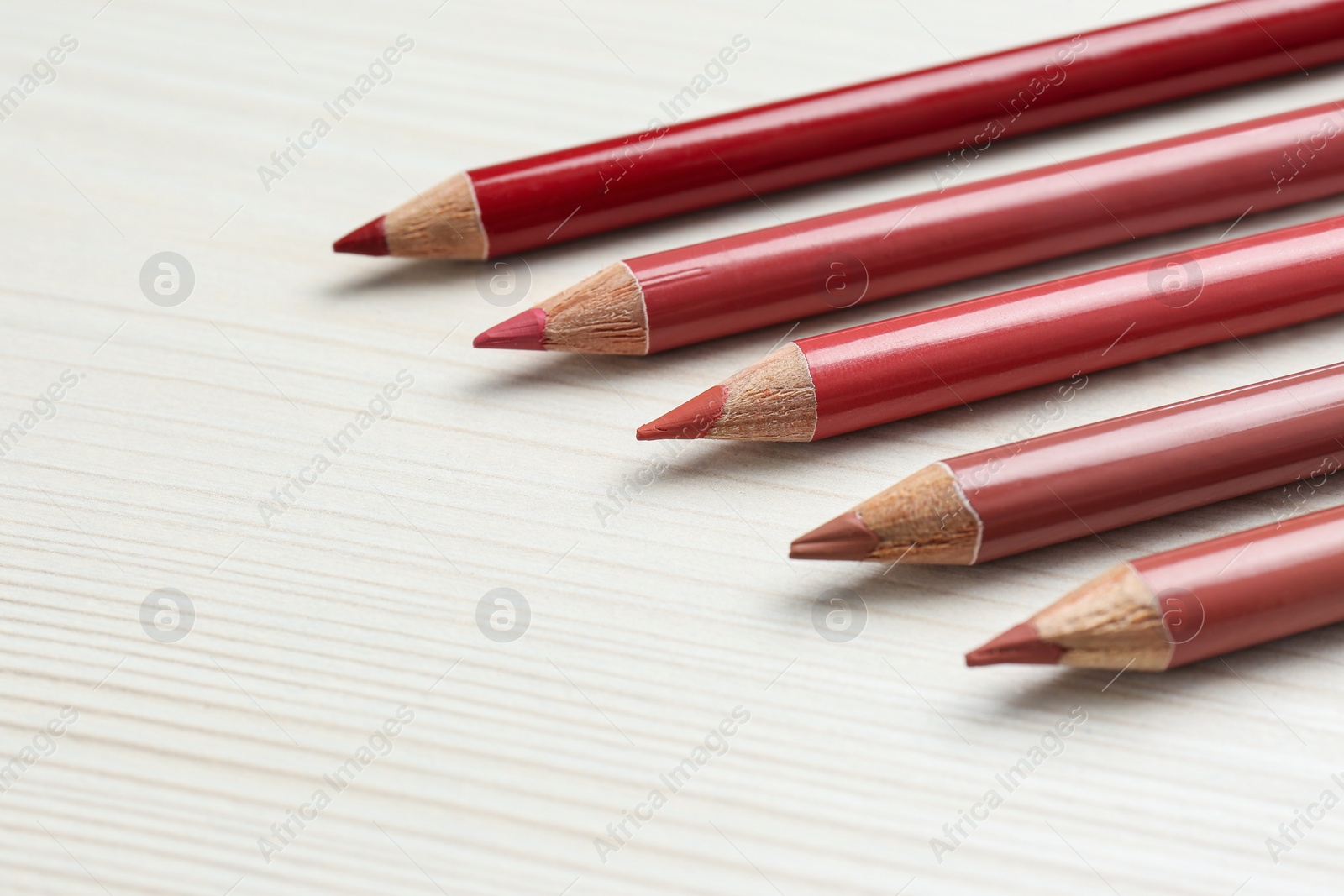 Photo of Many lip pencils on white wooden table, space for text