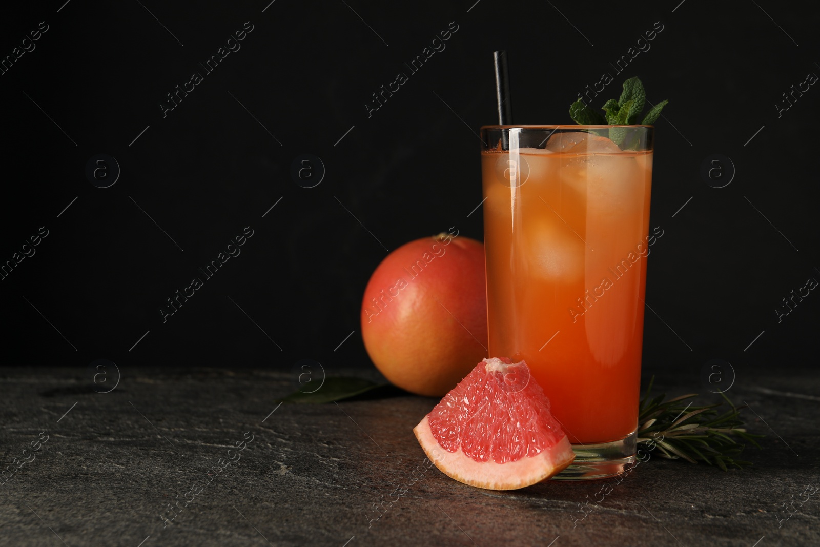 Photo of Tasty grapefruit drink with ice and mint in glass on dark textured table. Space for text