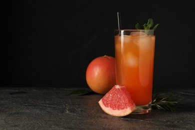 Photo of Tasty grapefruit drink with ice and mint in glass on dark textured table. Space for text