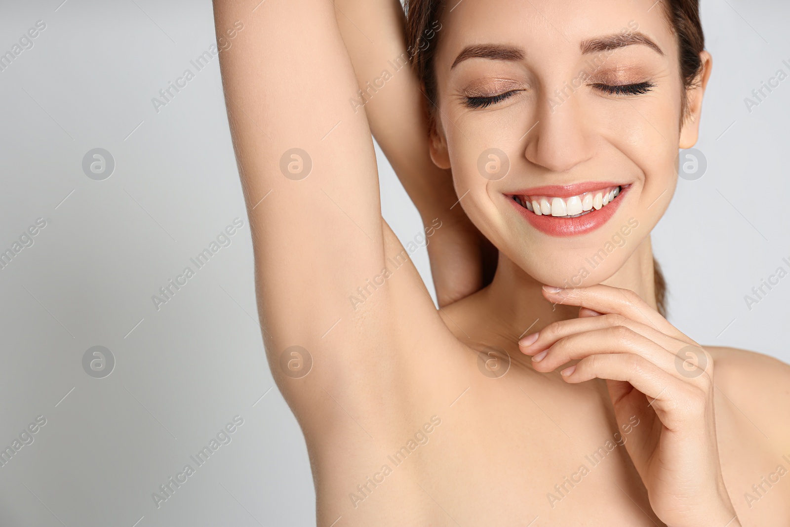 Photo of Young woman showing armpit with smooth clean skin on light grey background, closeup