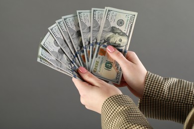 Photo of Woman holding banknotes on grey background, closeup. Money exchange concept