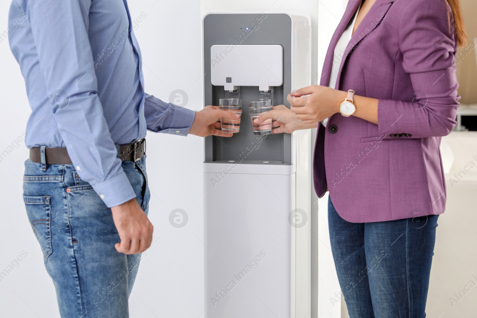 Photo of Employees taking glasses of water from cooler in office, closeup