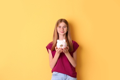 Photo of Teen girl with piggy bank on color background