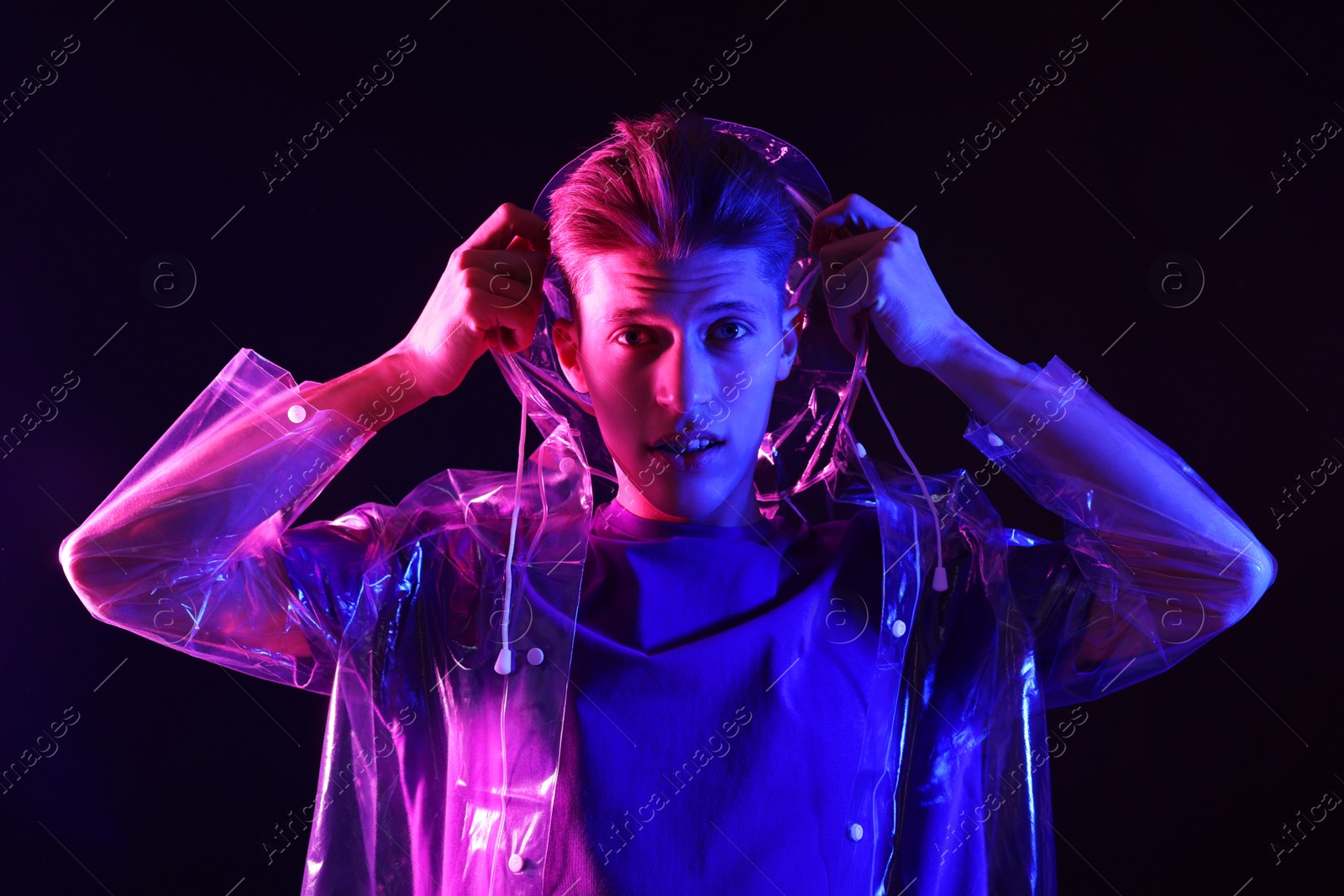 Photo of Young man wearing clear coat on dark background in neon lights