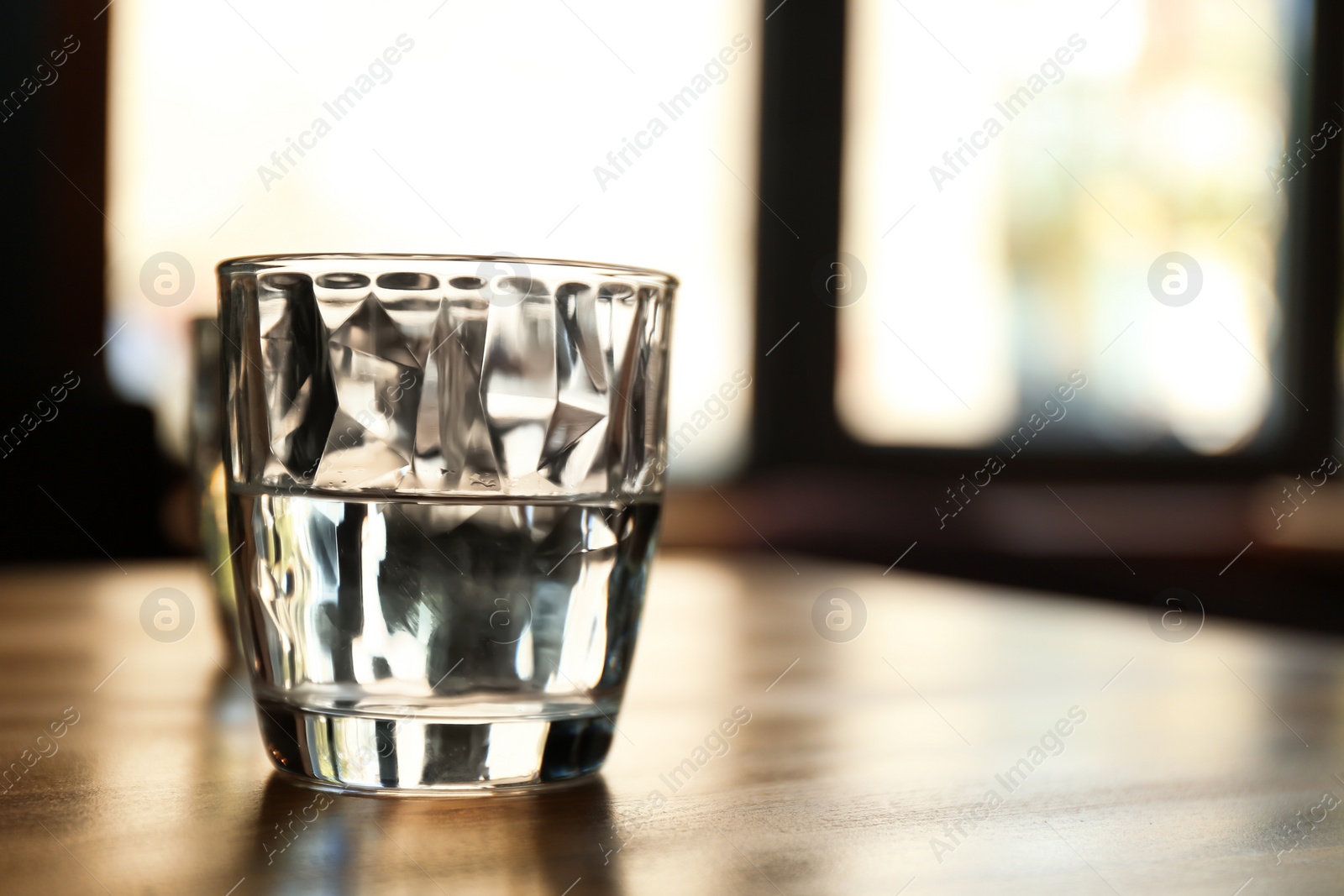 Photo of Glass of water on wooden table in cafe. Space for text