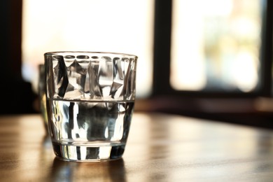 Photo of Glass of water on wooden table in cafe. Space for text