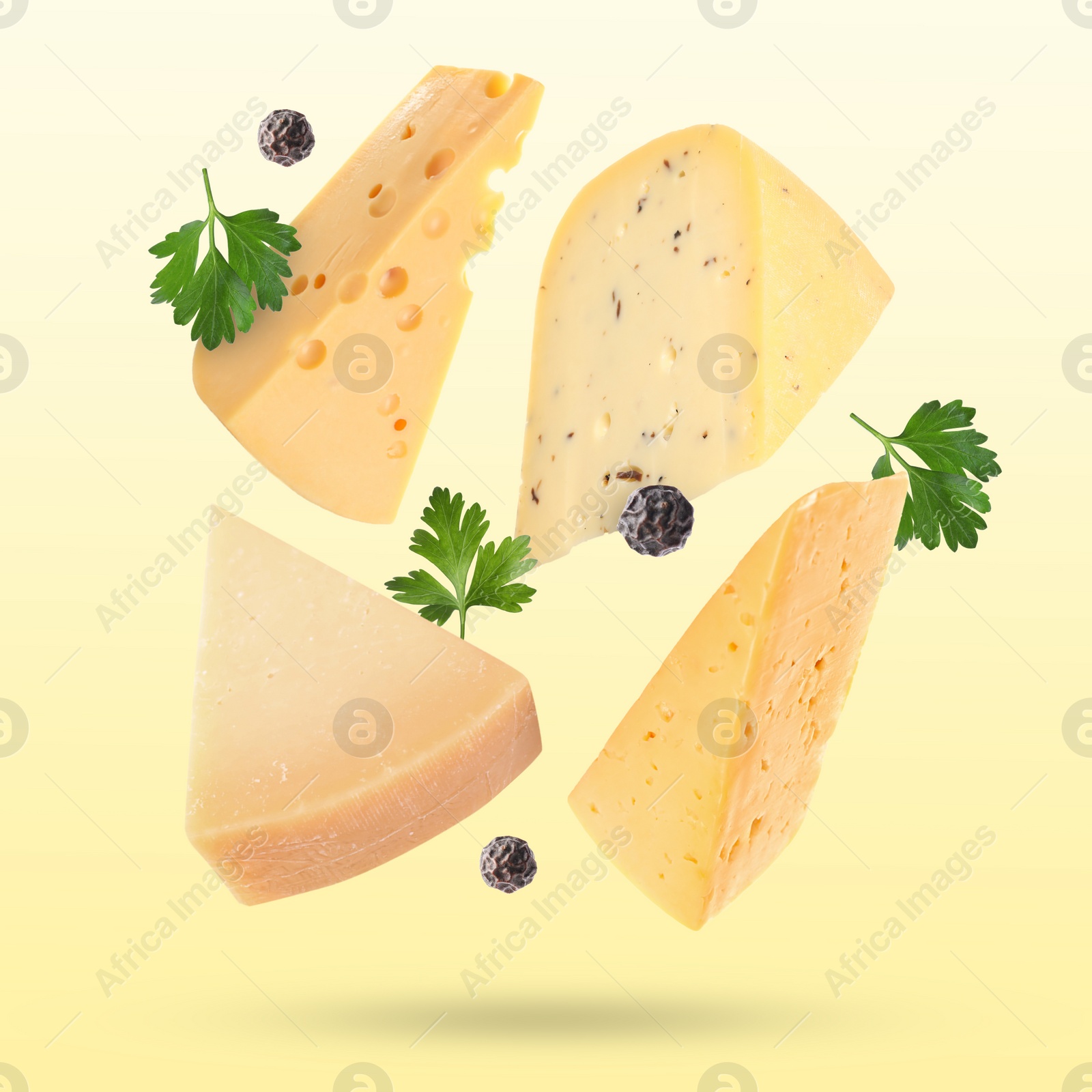 Image of Different kinds of cheese, parsley and peppercorns falling on light yellow background