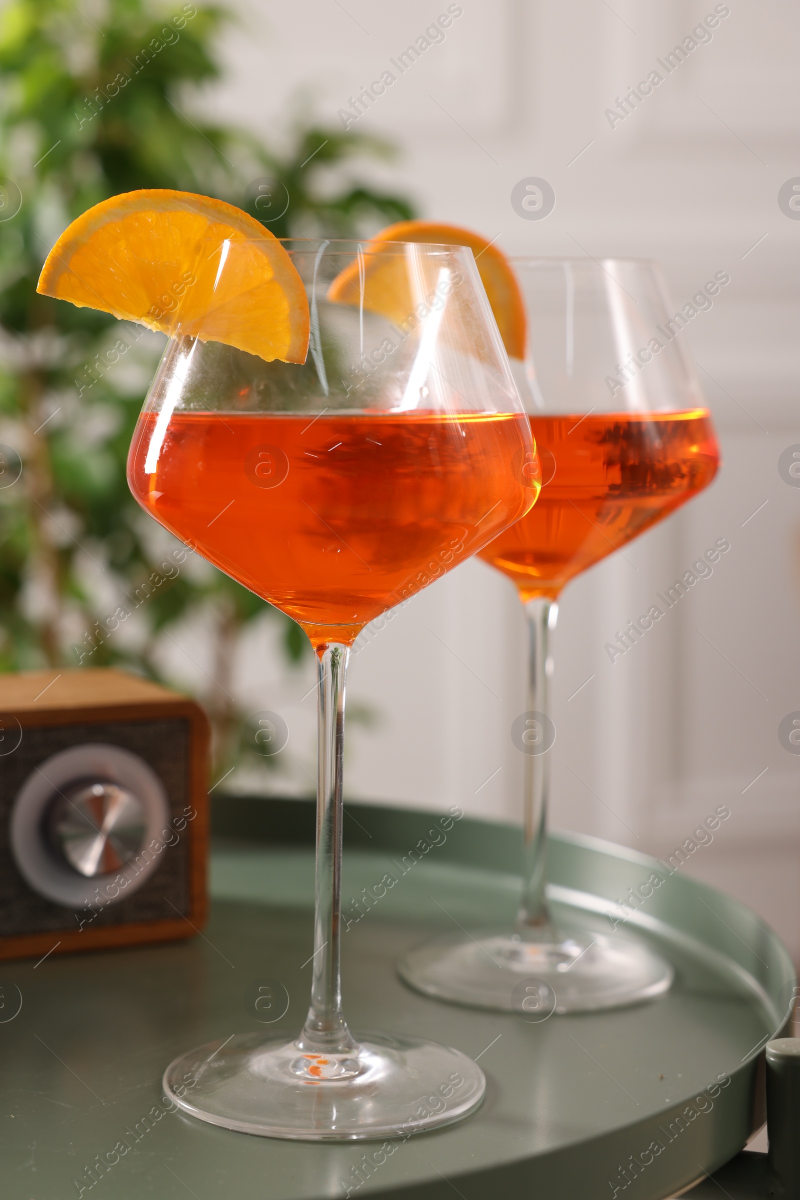 Photo of Tasty cocktail in glasses with orange slices on table in room. Relax at home