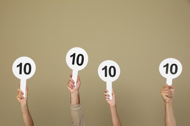 Photo of Panel of judges holding signs with highest score on beige background, closeup