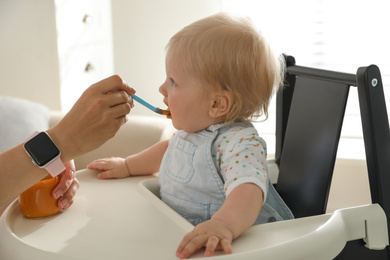 Photo of Mother feeding her cute little baby with healthy food at home