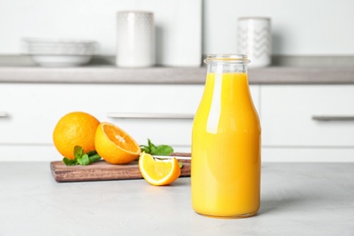 Photo of Bottle with fresh orange juice on table