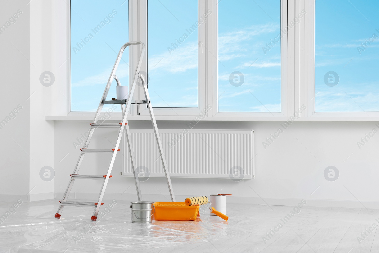 Photo of Stepladder and painting tools near window in empty room, space for text