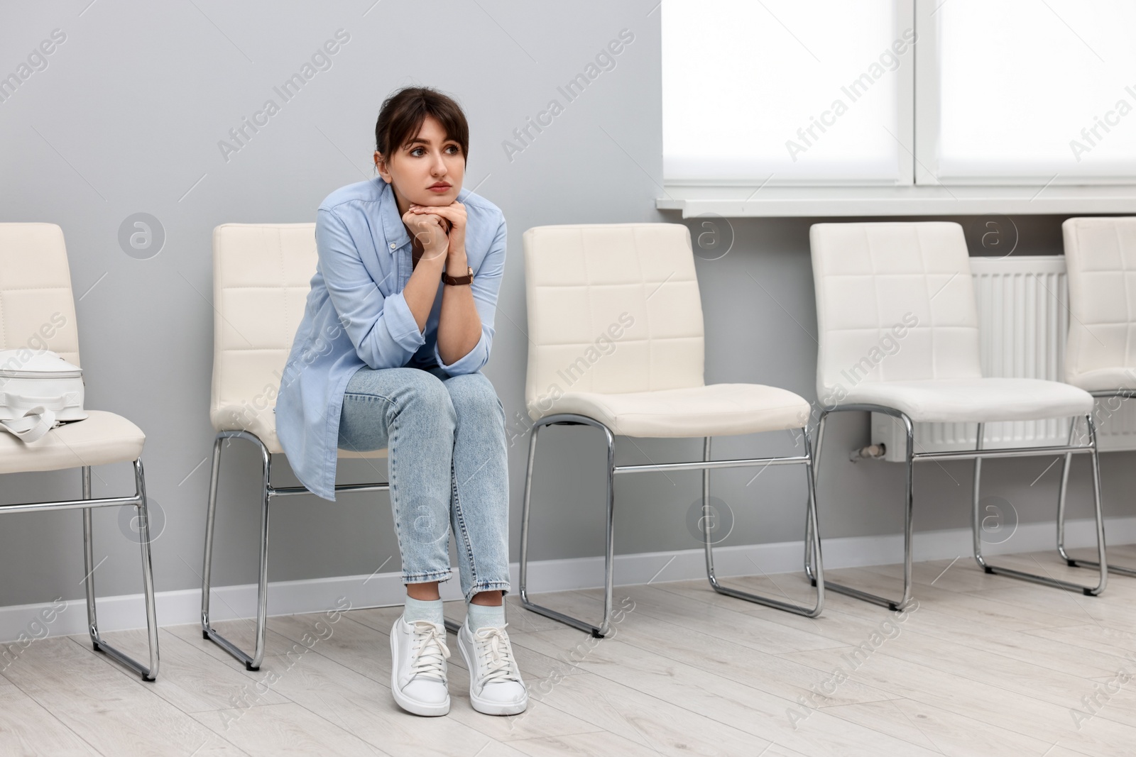 Photo of Woman sitting on chair and waiting for appointment indoors