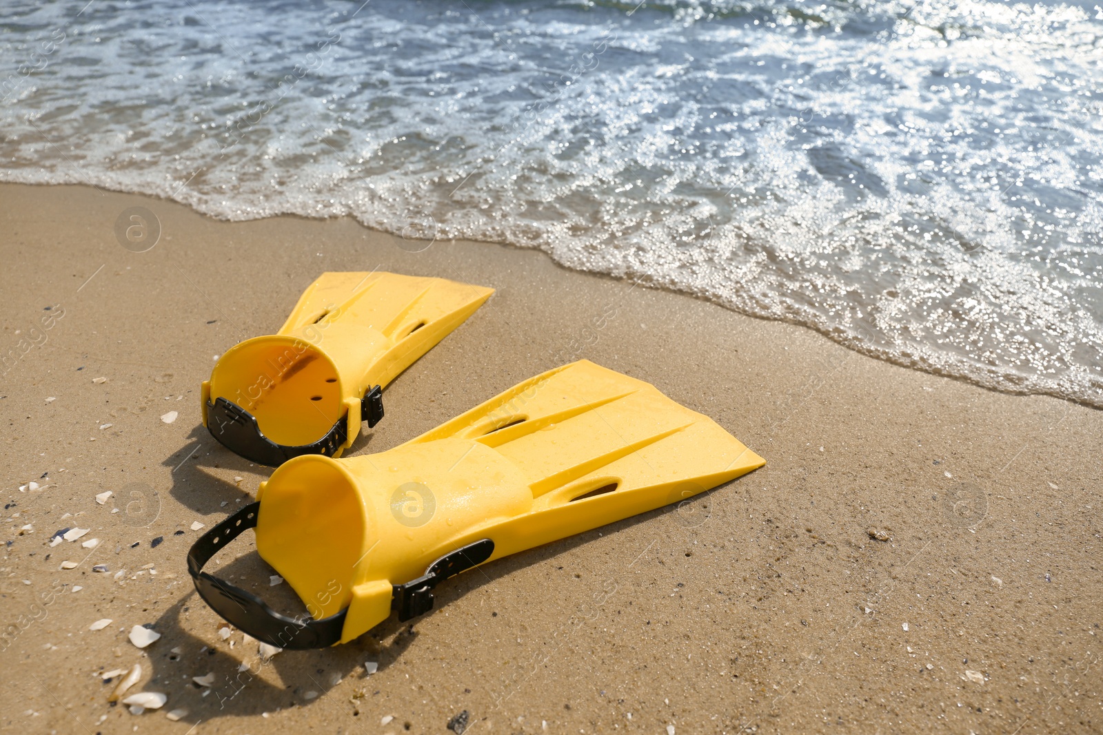 Photo of Pair of yellow flippers on sand near sea. Space for text