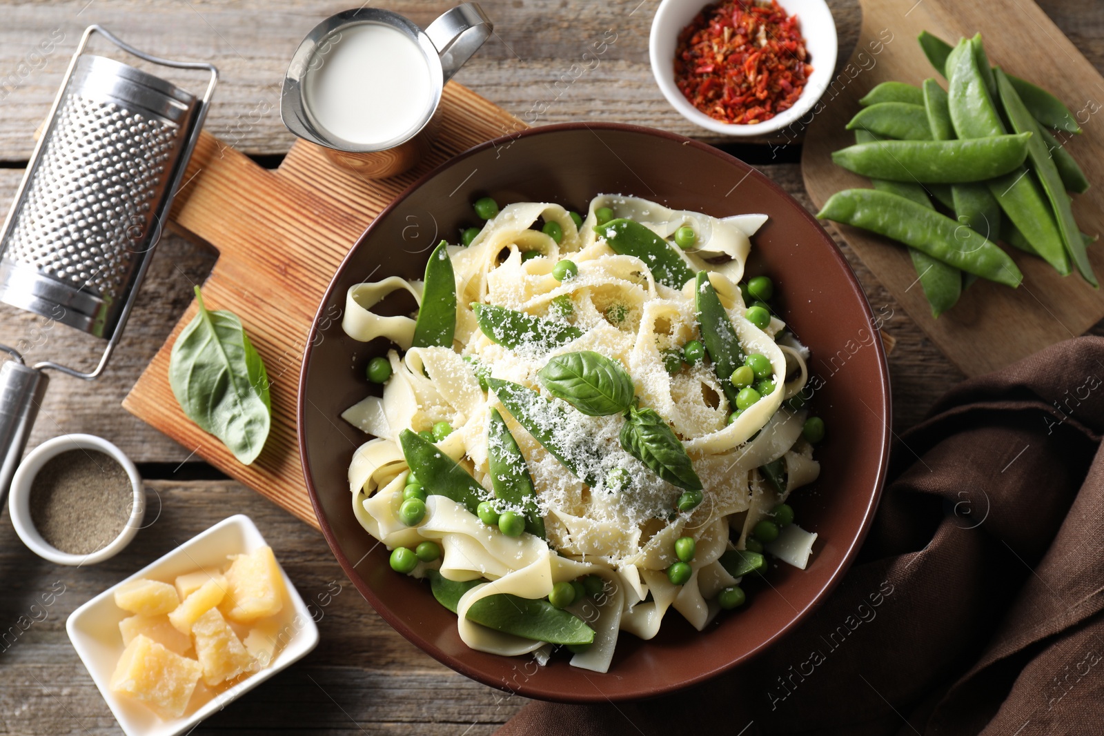 Photo of Delicious pasta with green peas and ingredients on wooden table, flat lay