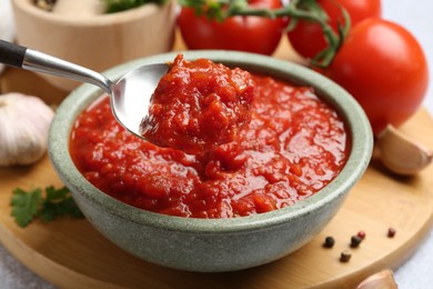 Photo of Eating homemade tomato sauce at light grey table, closeup