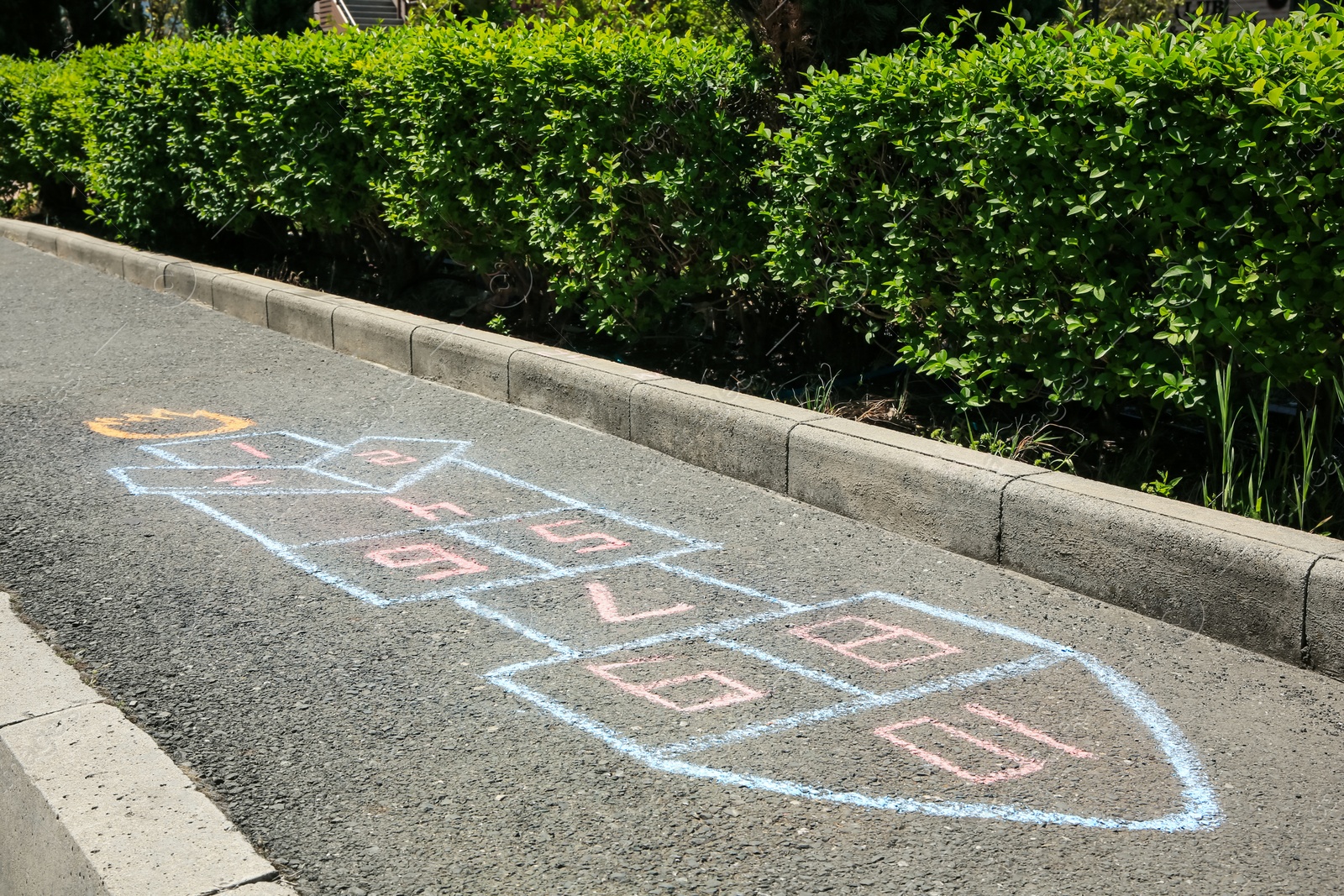 Photo of Hopscotch drawn with colorful chalk on asphalt outdoors