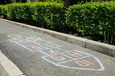 Hopscotch drawn with colorful chalk on asphalt outdoors