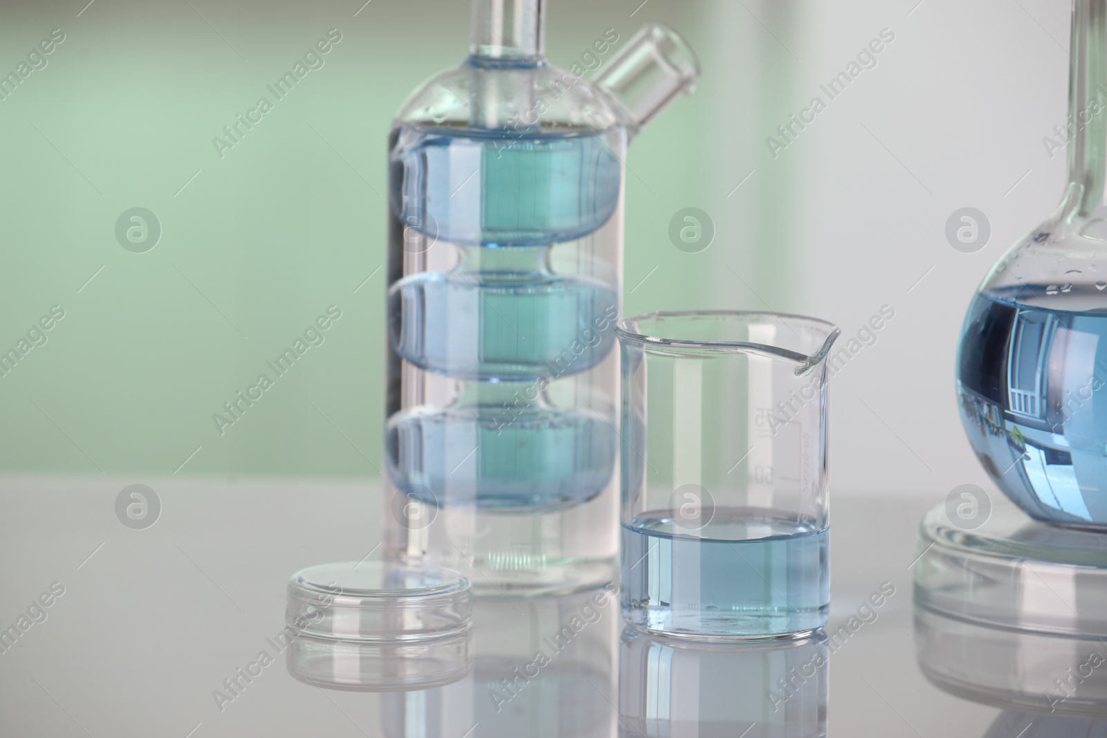 Photo of Laboratory analysis. Different glassware with liquid on white table against blurred background. Space for text