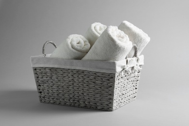 Photo of Basket with rolled towels on light background