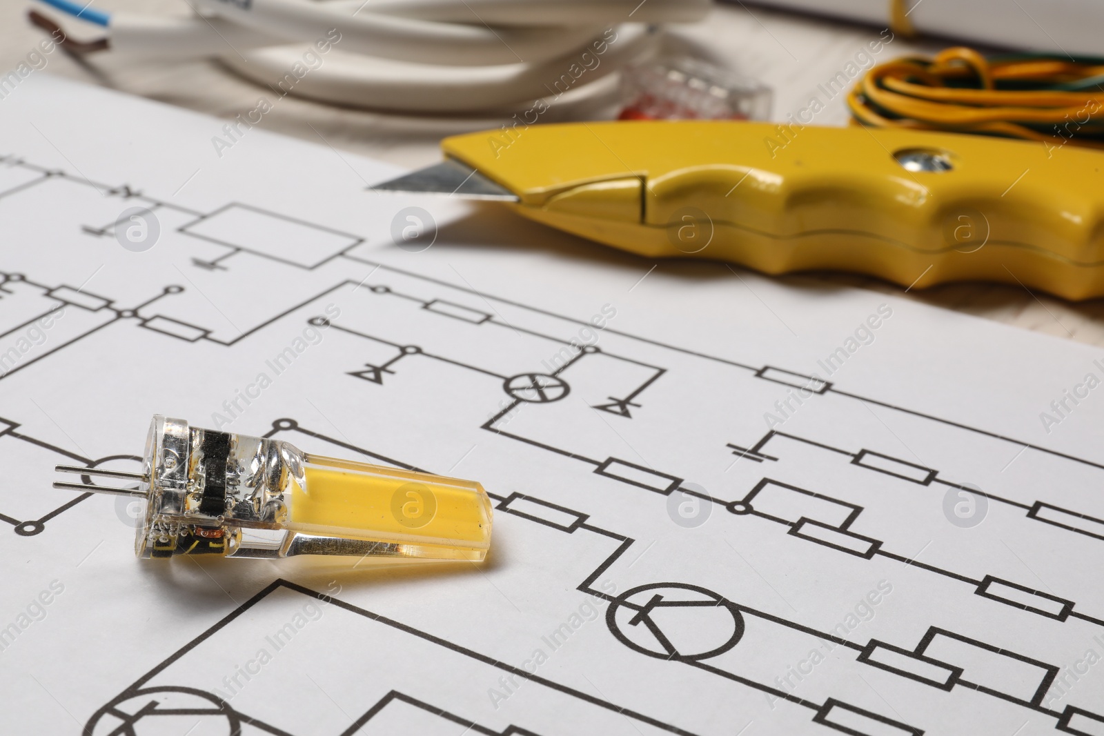 Photo of Wiring diagram, knife and electrician's equipment on white table, closeup