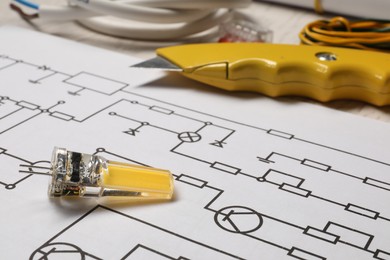 Wiring diagram, knife and electrician's equipment on white table, closeup