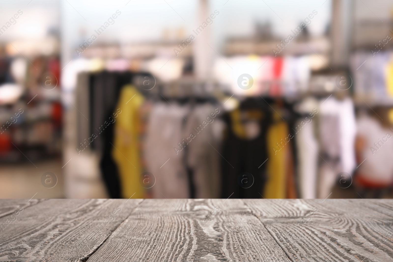 Image of Empty wooden table and blurred view of store with modern clothes