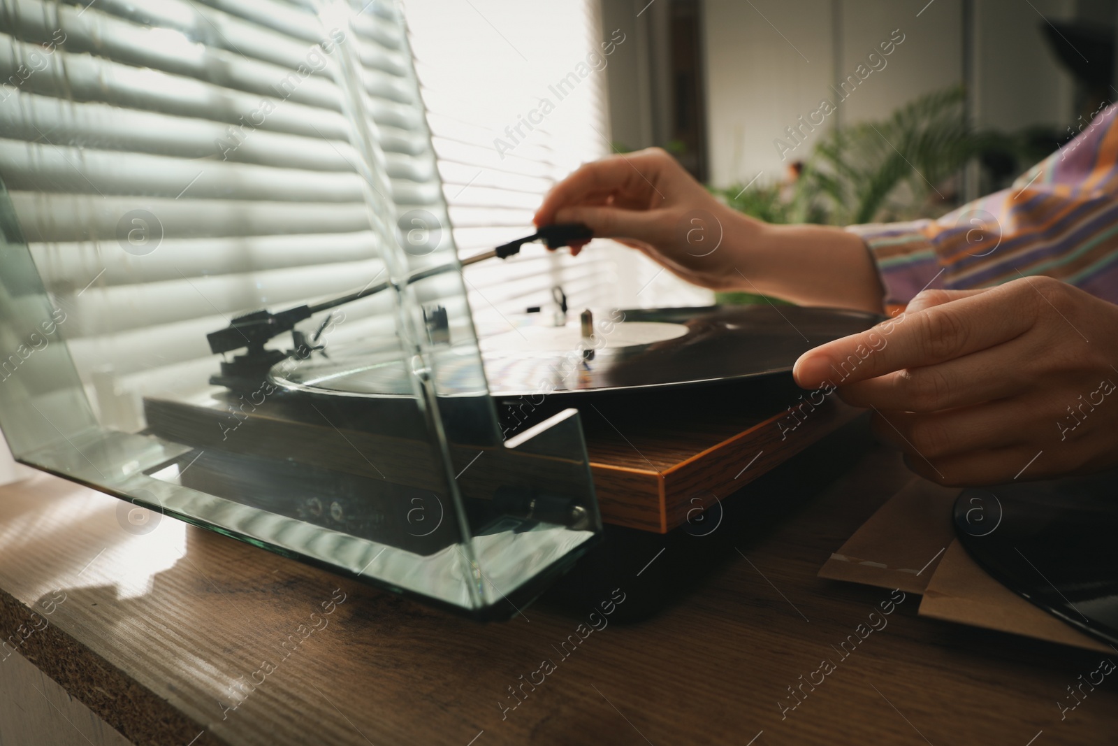 Photo of Young woman using turntable at home, closeup