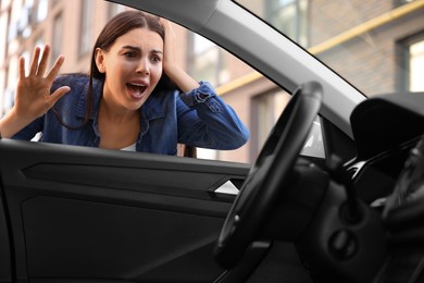 Photo of Automobile lockout, key forgotten inside. Emotional woman looking through car window