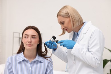 Trichologist with dermatoscope examining patient`s hair in clinic