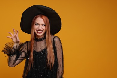 Photo of Happy young woman in scary witch costume on orange background, space for text. Halloween celebration