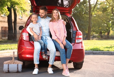 Photo of Happy family sitting in car's trunk outdoors
